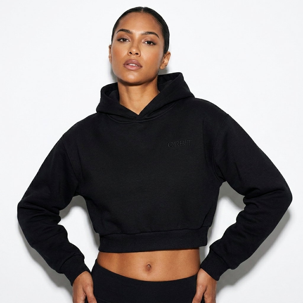 Essential Cropped Hoodie worn by a toned Brazilian female fashion influencer, gorpcore outdoor styling, studio lookbook — custom essential cropped hoodie