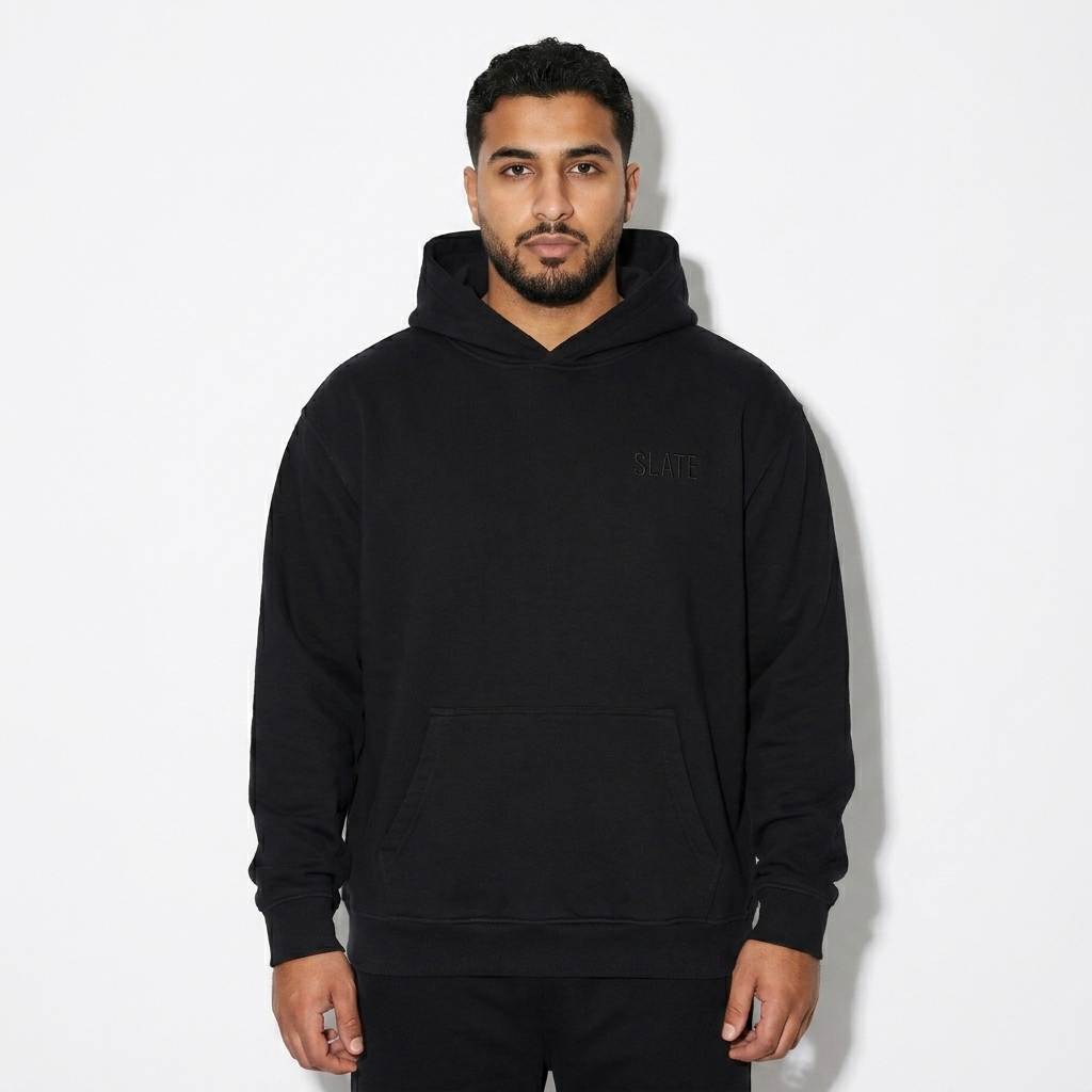 Oversized Essential Hoodie worn by a mid-size Arab male fashion influencer, clean-girl minimal styling, studio lookbook — custom oversized essential hoodie