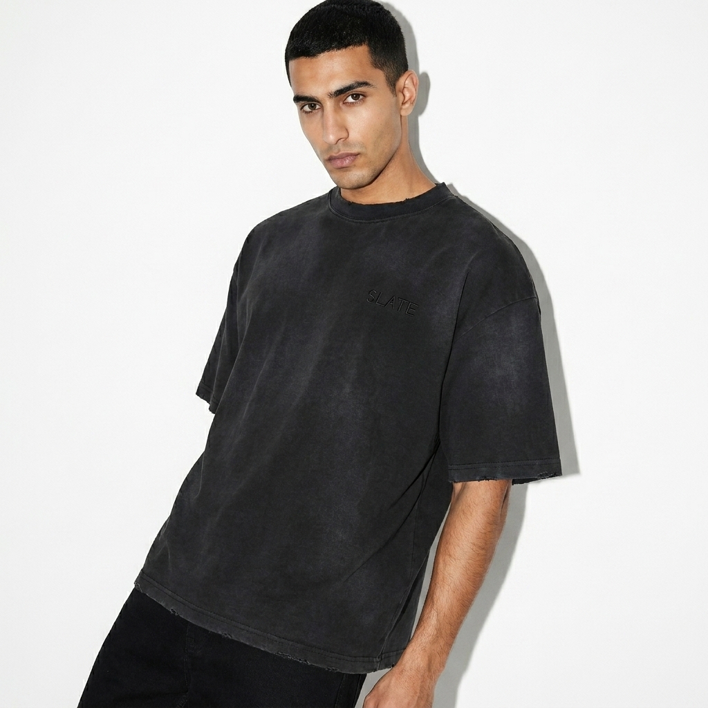 Unisex Distressed Boxy T-Shirt worn by a lean Middle Eastern male fashion influencer, gorpcore outdoor styling, studio lookbook — custom unisex distressed boxy t-shirt